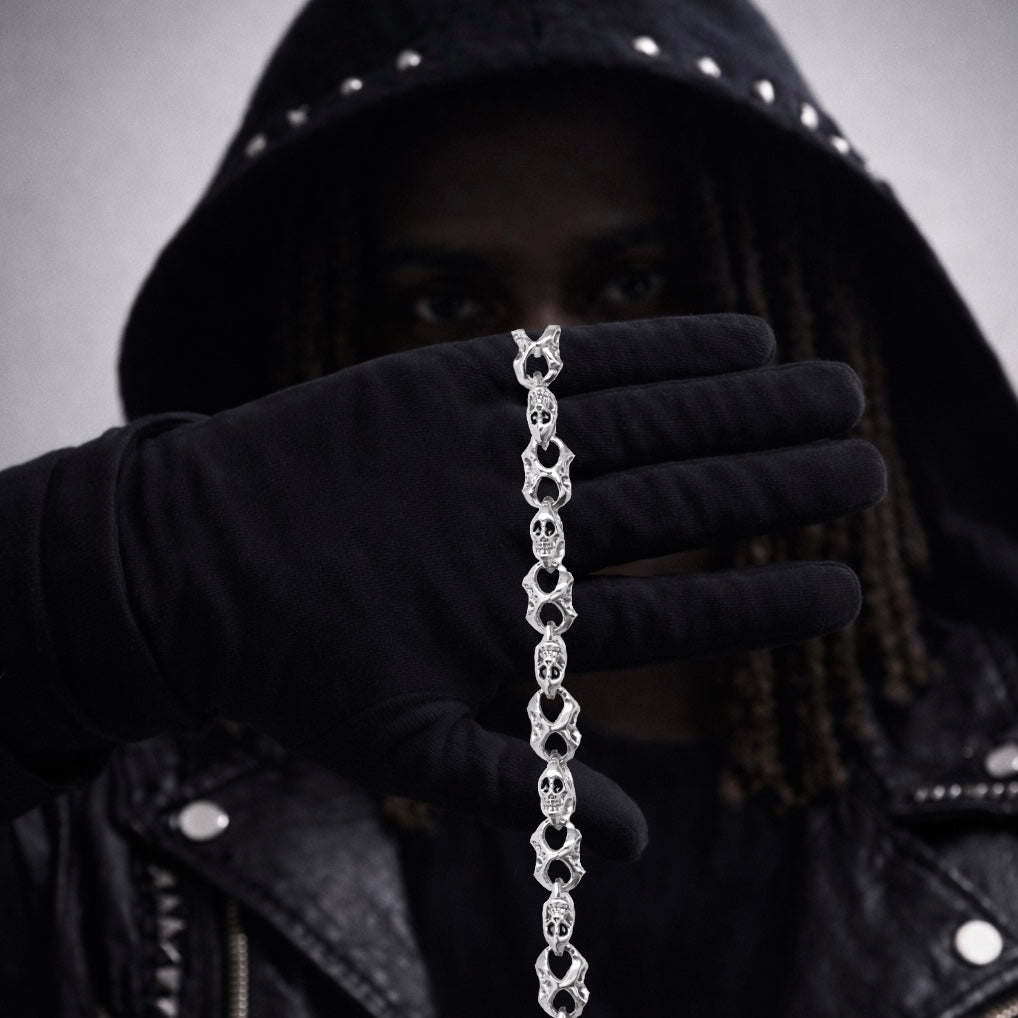 Person wearing a black hooded jacket holding a silver chain bracelet.