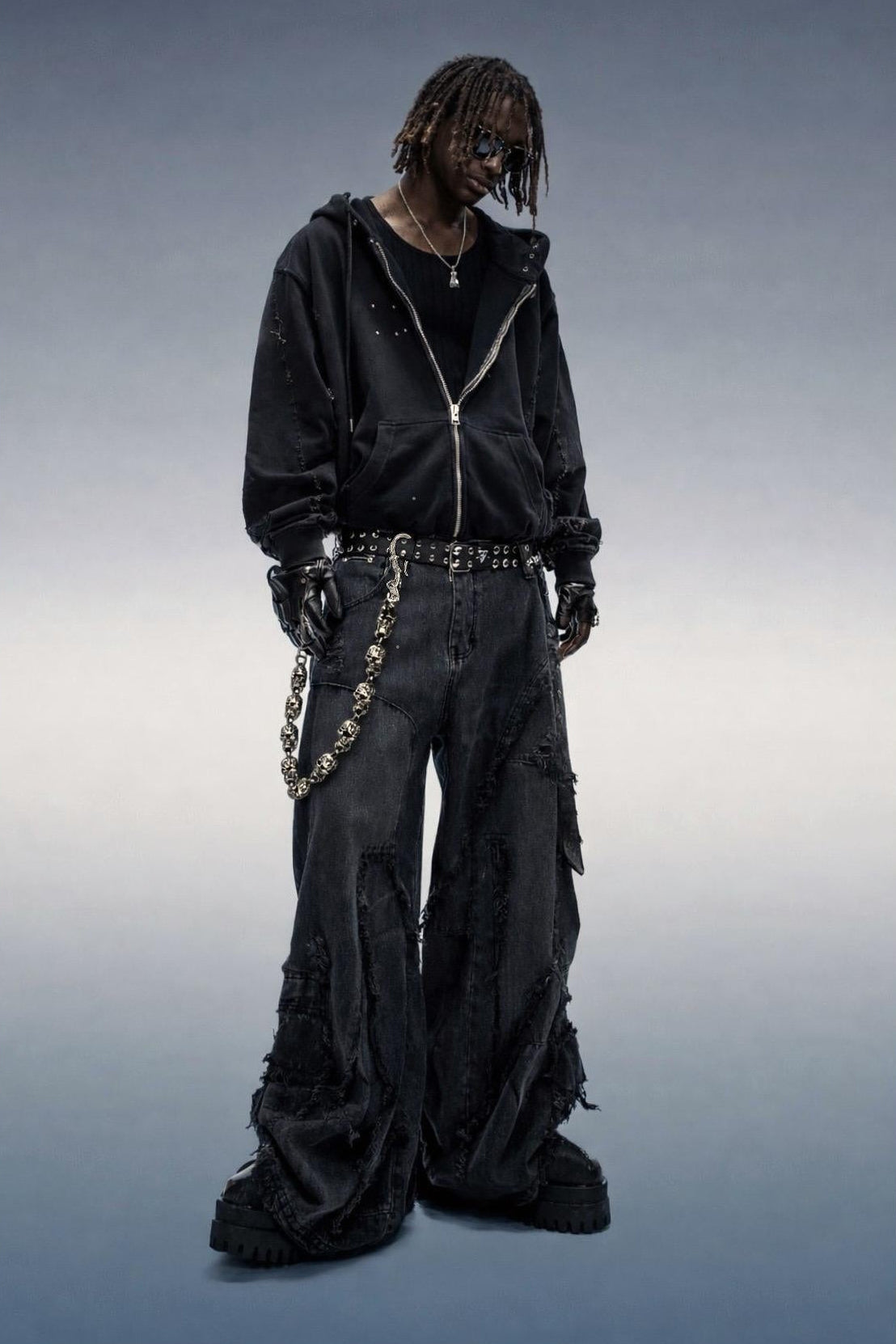 Person wearing a black outfit with chains on a gradient background